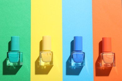 Photo of Nail polishes in bottles on color background, flat lay. Space for text