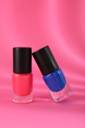 Photo of Nail polishes in bottles on pink background