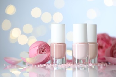 Photo of Nail polishes in bottles, beads and beautiful flowers on white table, closeup. Space for text