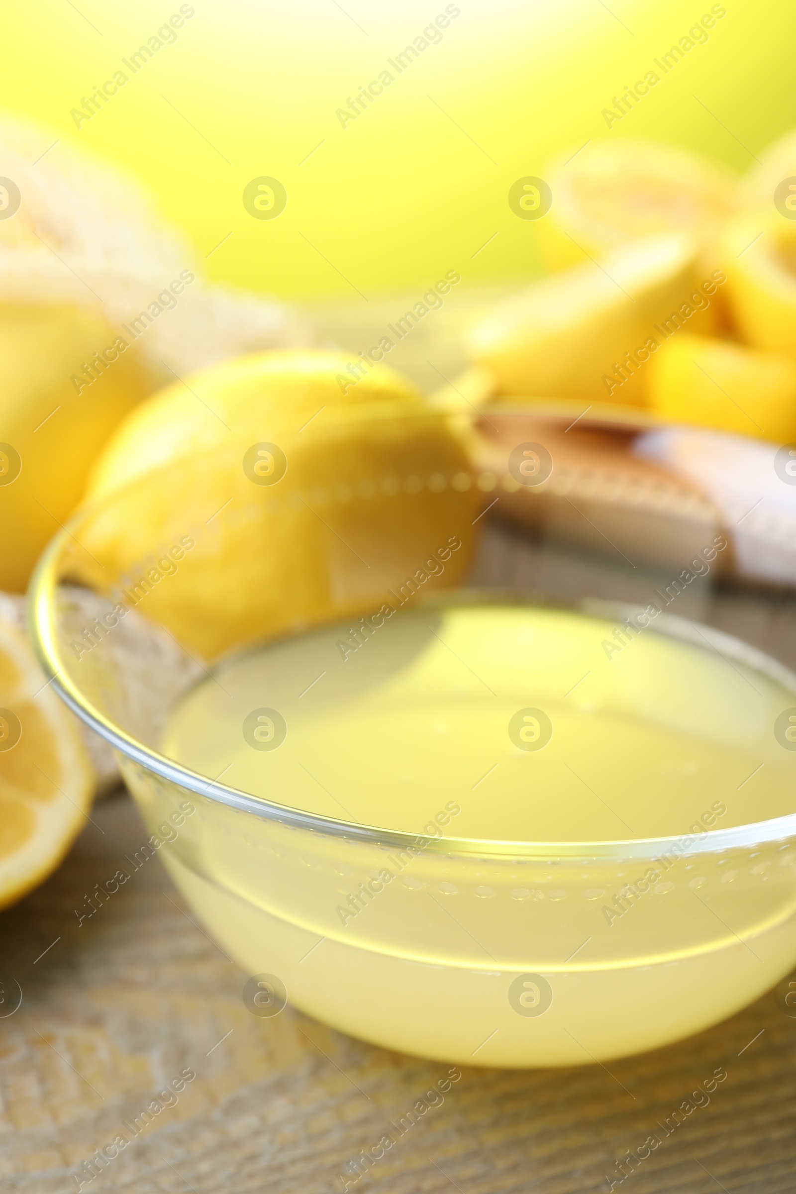 Photo of Bowl with fresh lemon juice and fruits on wooden table, closeup