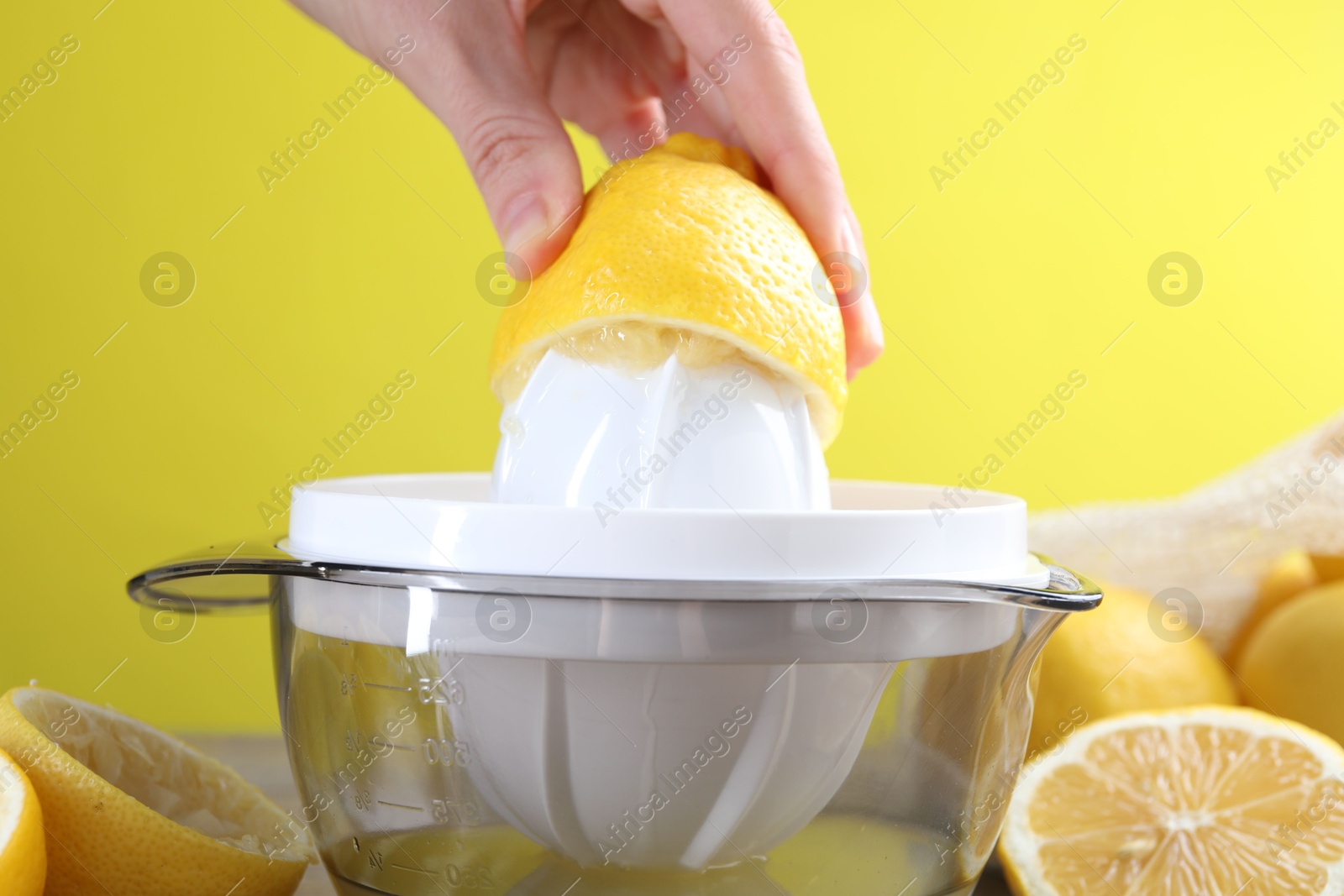 Photo of Woman with lemon using juicer at wooden table, closeup