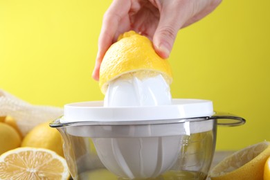 Photo of Woman with lemon using juicer at wooden table, closeup