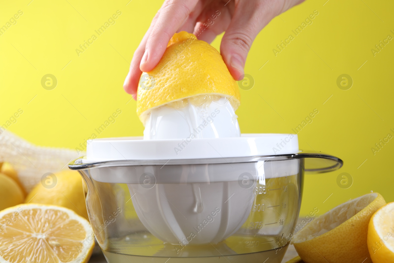 Photo of Woman with lemon using juicer at wooden table, closeup