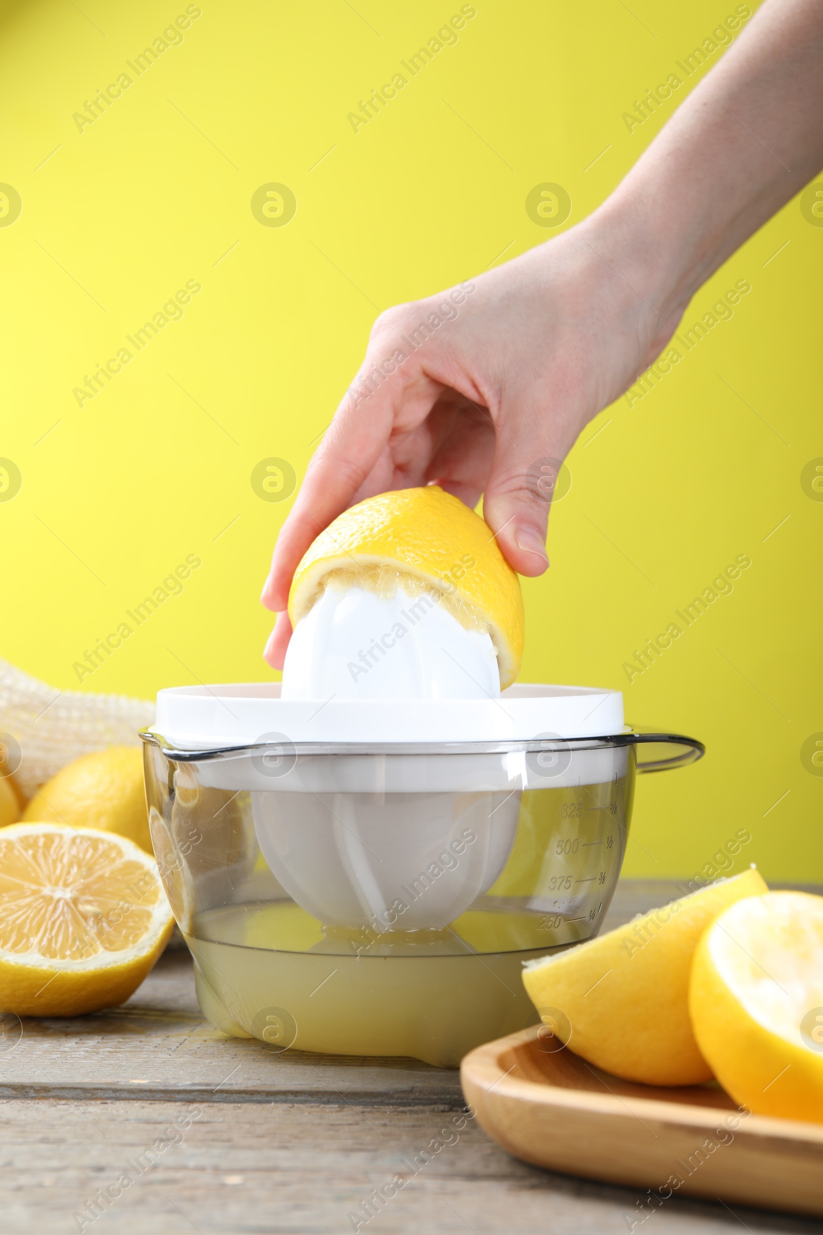 Photo of Woman with lemon using juicer at wooden table, closeup