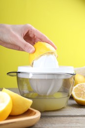 Photo of Woman with lemon using juicer at wooden table, closeup