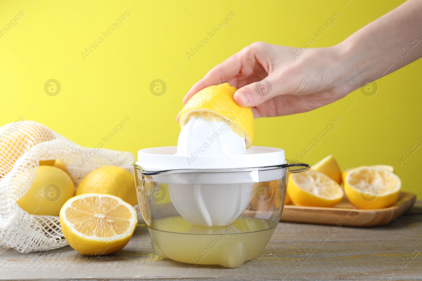 Photo of Woman with lemon using juicer at wooden table, closeup