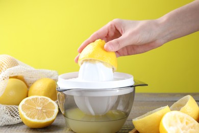 Photo of Woman with lemon using juicer at wooden table, closeup