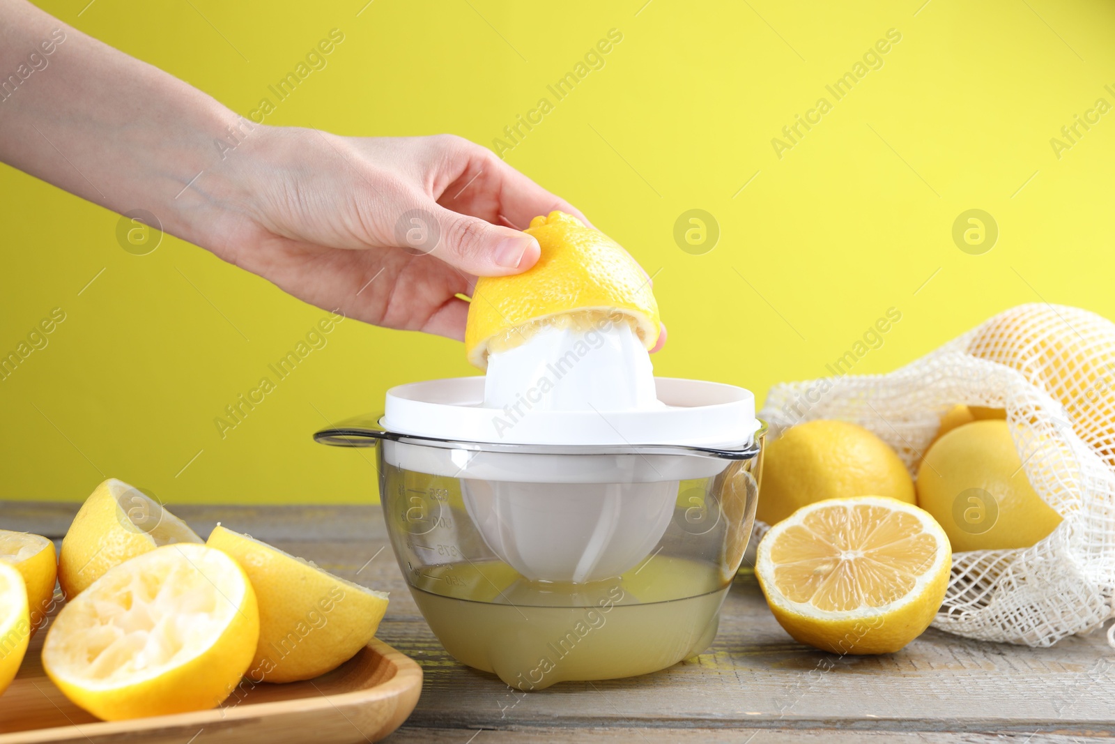 Photo of Woman with lemon using juicer at wooden table, closeup