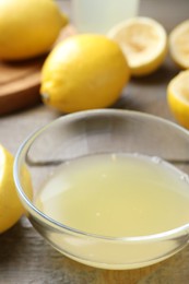 Photo of Bowl with fresh lemon juice and fruits on wooden table, closeup