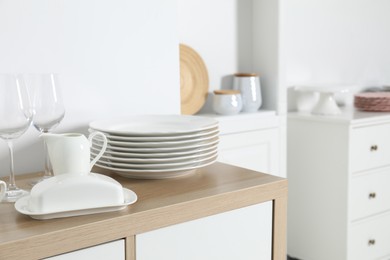 Photo of Tableware on wooden storage cabinet near white wall indoors