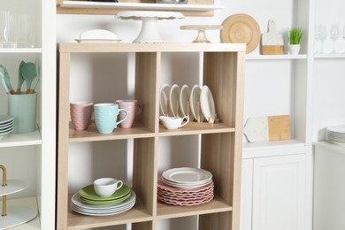 Photo of Shelving units with kitchenware near white wall indoors