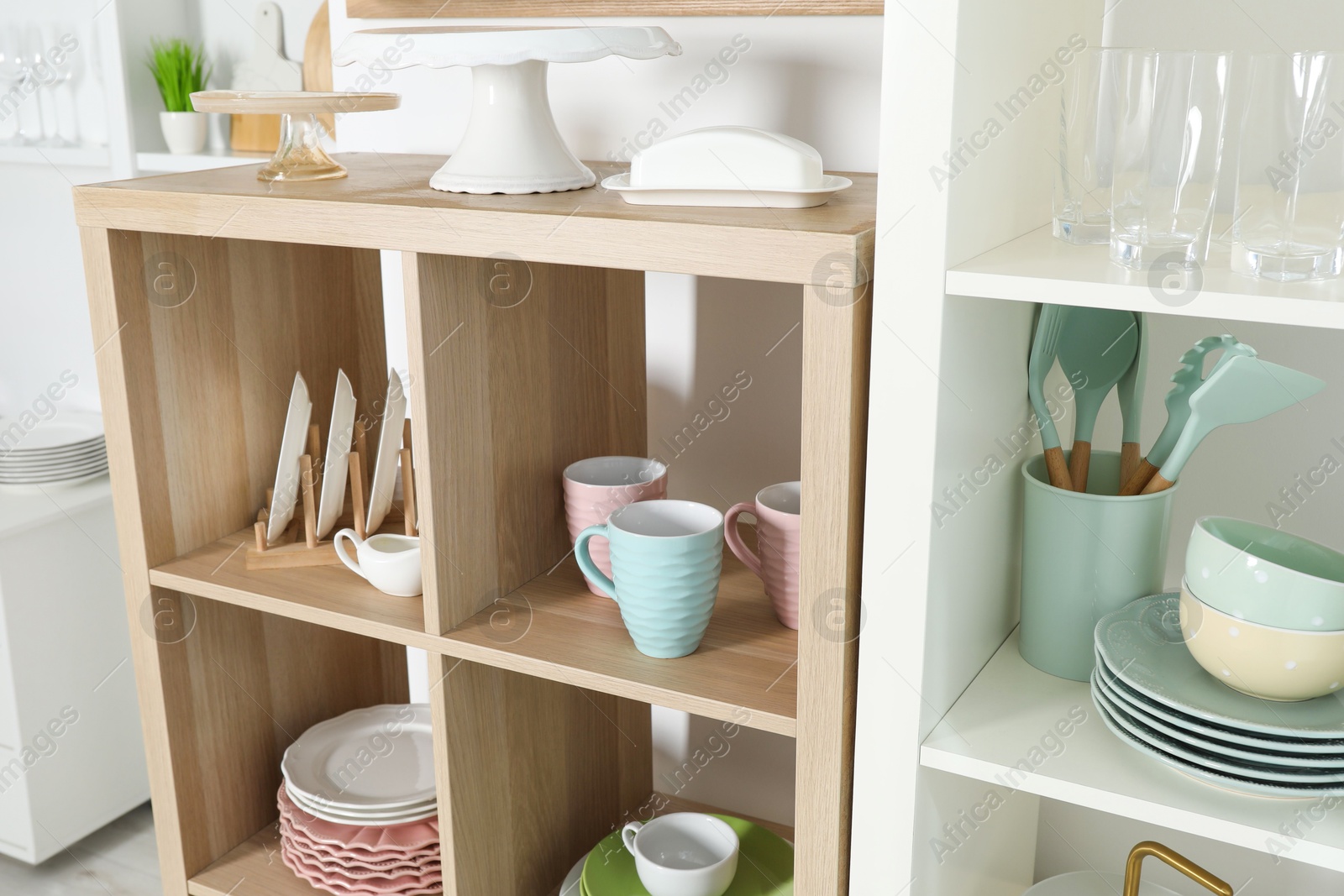 Photo of Shelving units with kitchenware near white wall indoors