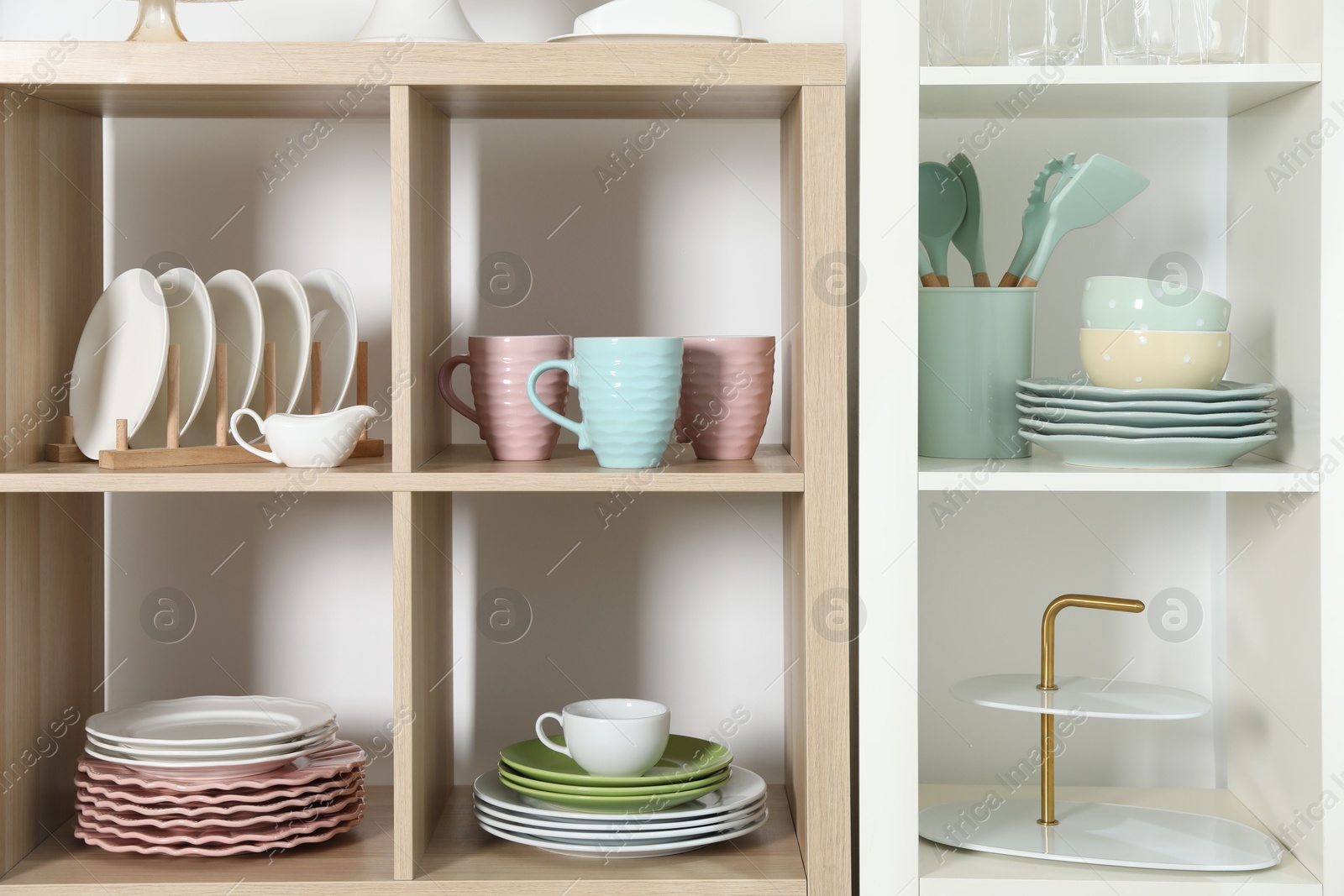 Photo of Shelving units with kitchenware near white wall indoors