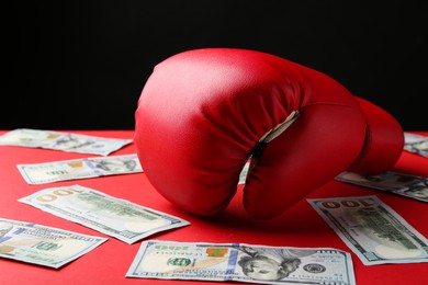 Photo of Boxing glove and dollar banknotes on red table