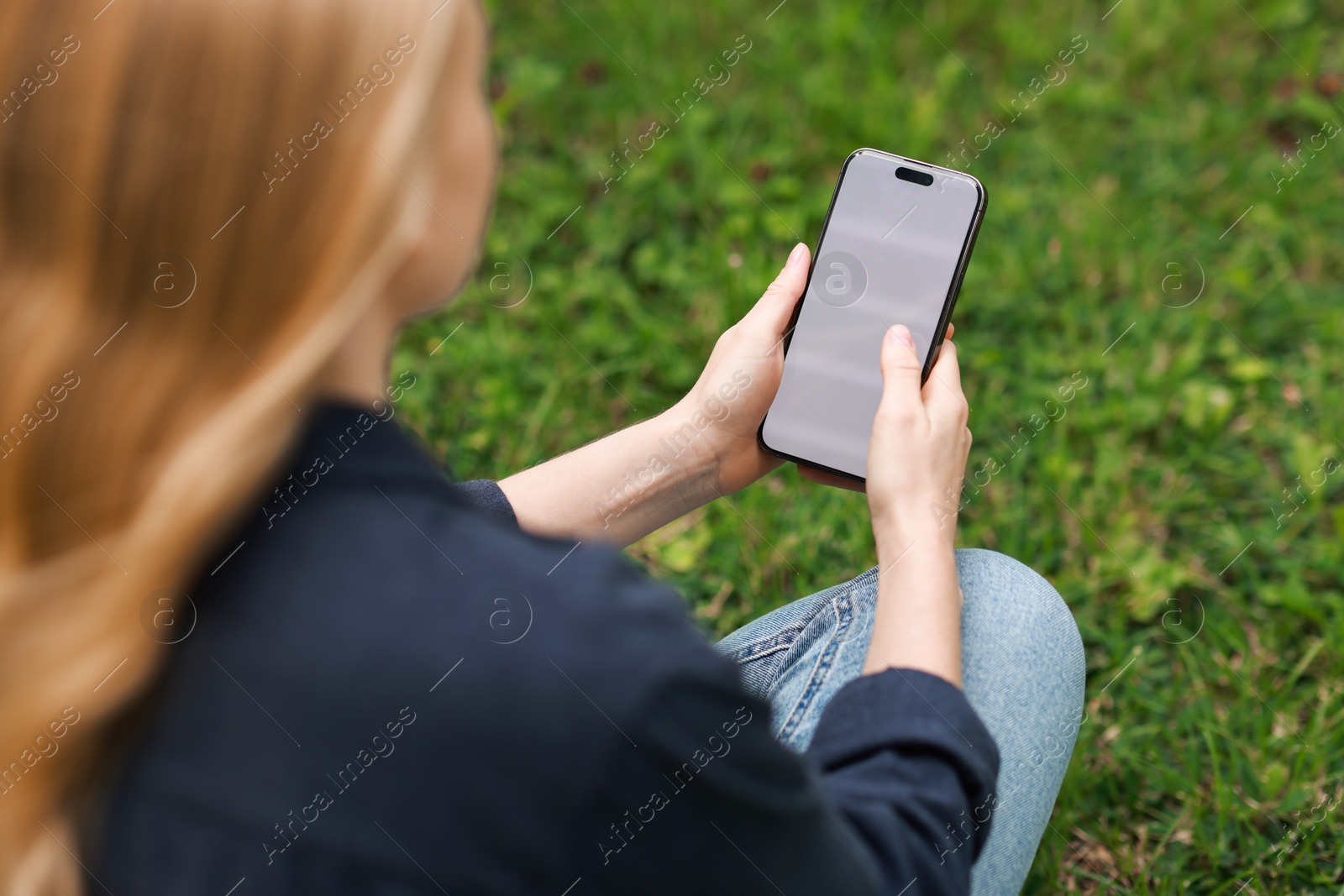 Photo of Woman using smartphone on green grass outdoors