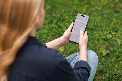 Woman using smartphone on green grass outdoors