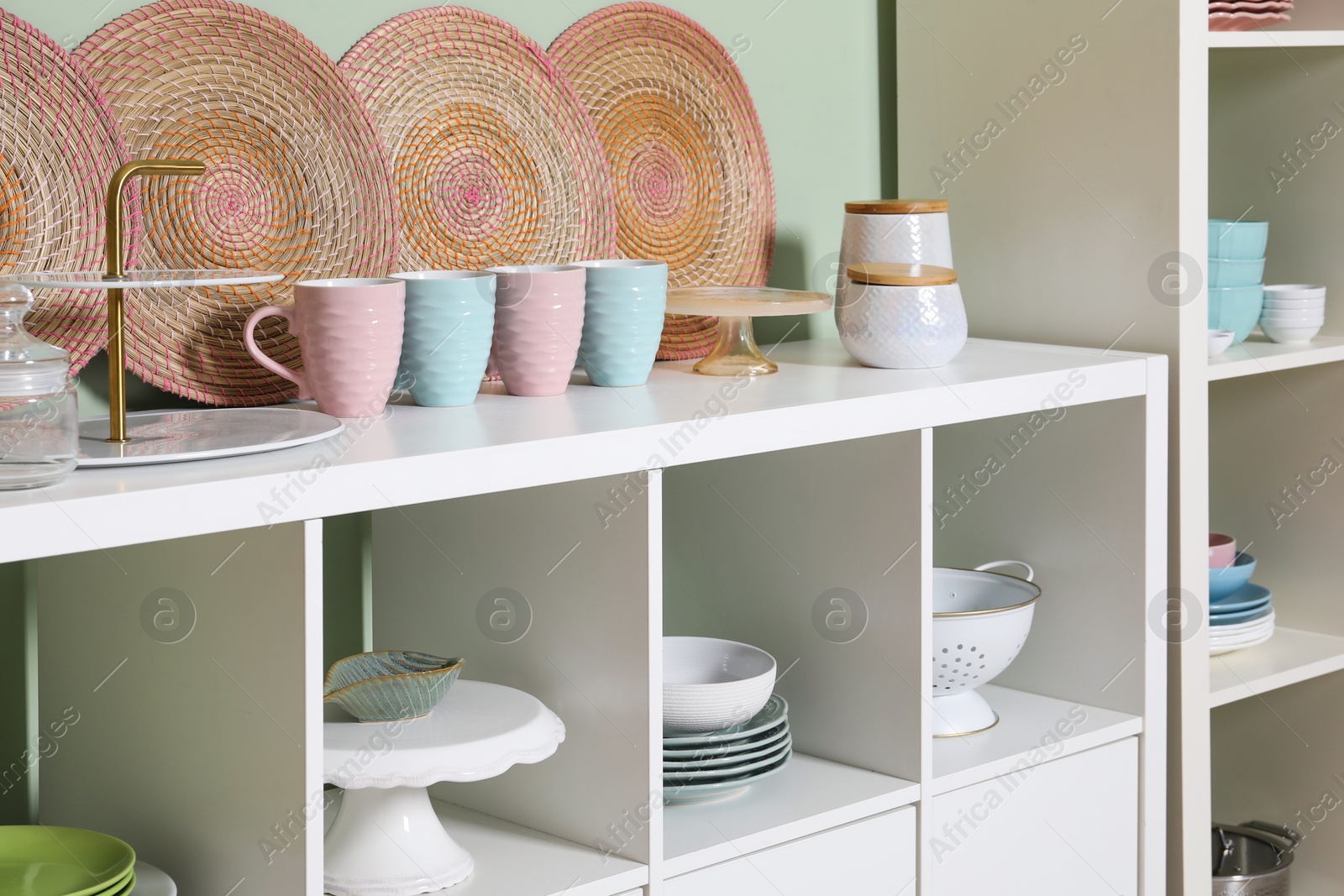 Photo of Shelving unit and storage cabinet with kitchenware near green wall