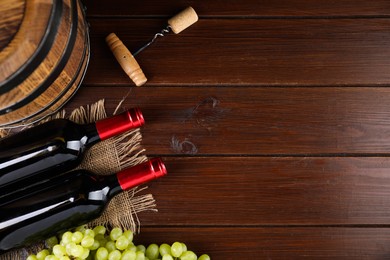 Photo of Corkscrew, bottles of wine, grapes and barrel on wooden table, top view. Space for text