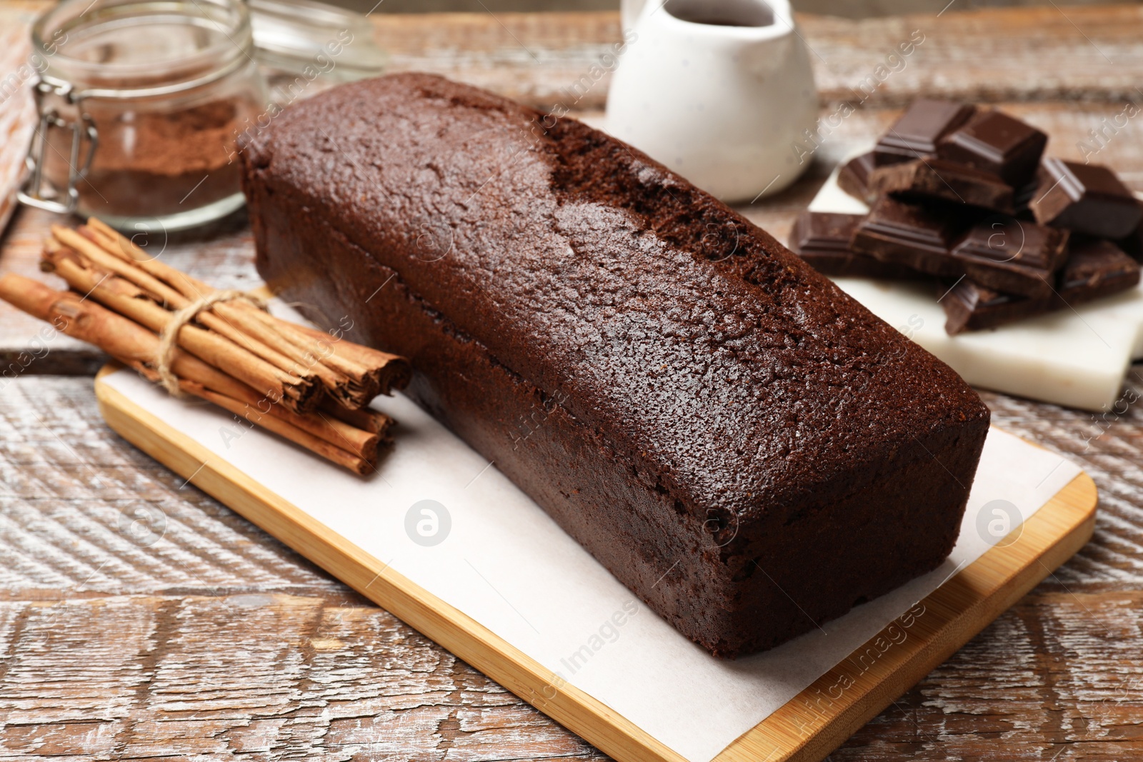 Photo of Tasty chocolate sponge cake and ingredients on wooden table, closeup