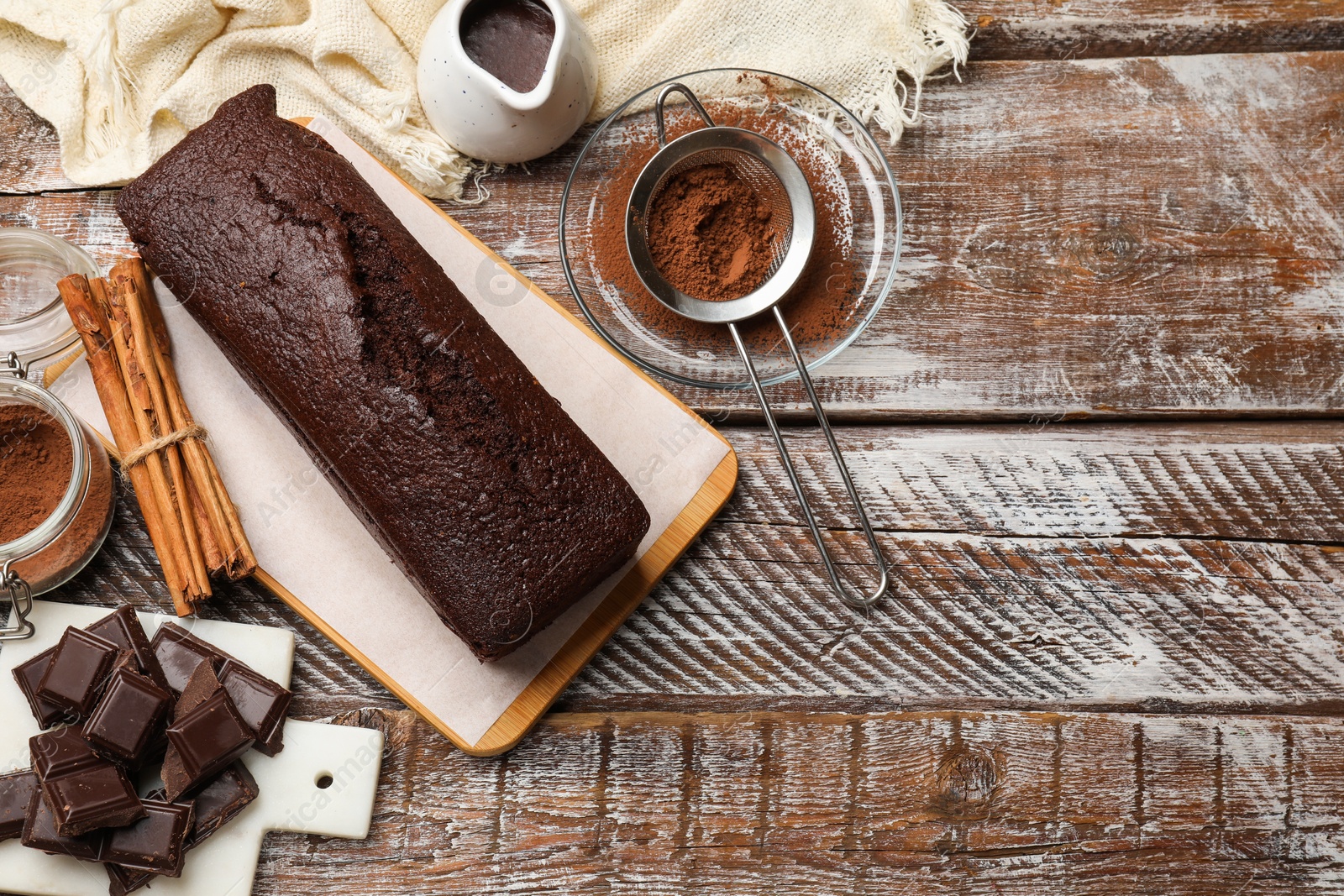 Photo of Tasty chocolate sponge cake and ingredients on wooden table, flat lay. Space for text