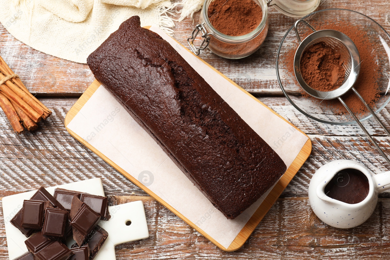 Photo of Tasty chocolate sponge cake and ingredients on wooden table, flat lay