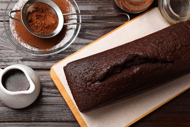 Photo of Tasty chocolate sponge cake and ingredients on wooden table, flat lay