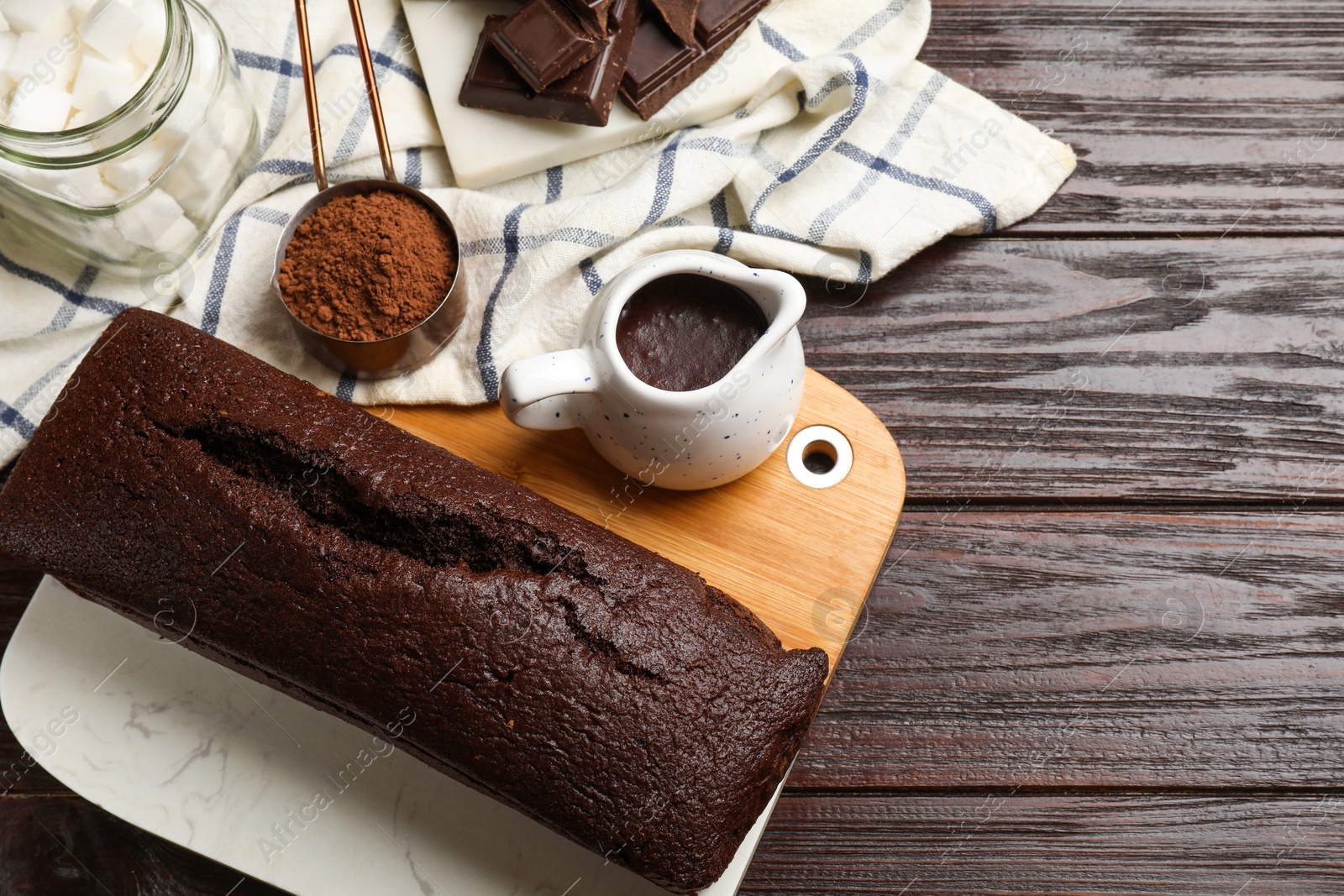 Photo of Tasty chocolate sponge cake and ingredients on wooden table, above view. Space for text