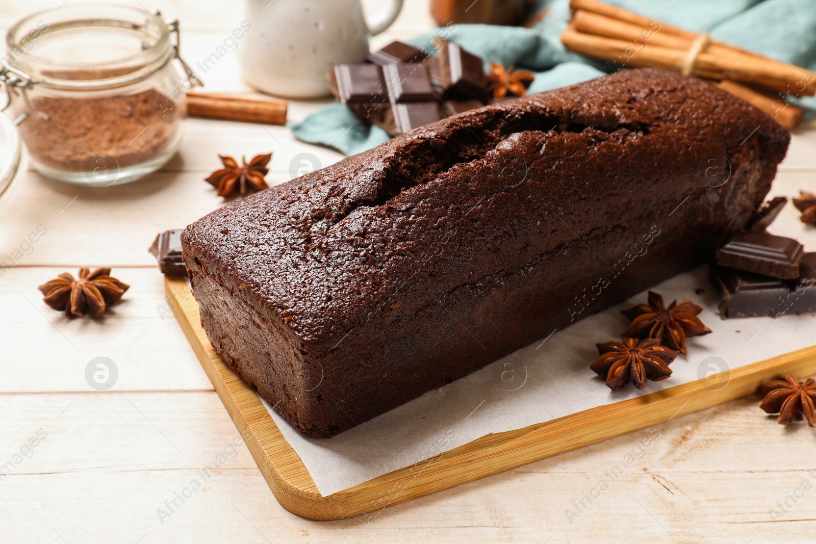 Photo of Tasty chocolate sponge cake and ingredients on white wooden table, closeup