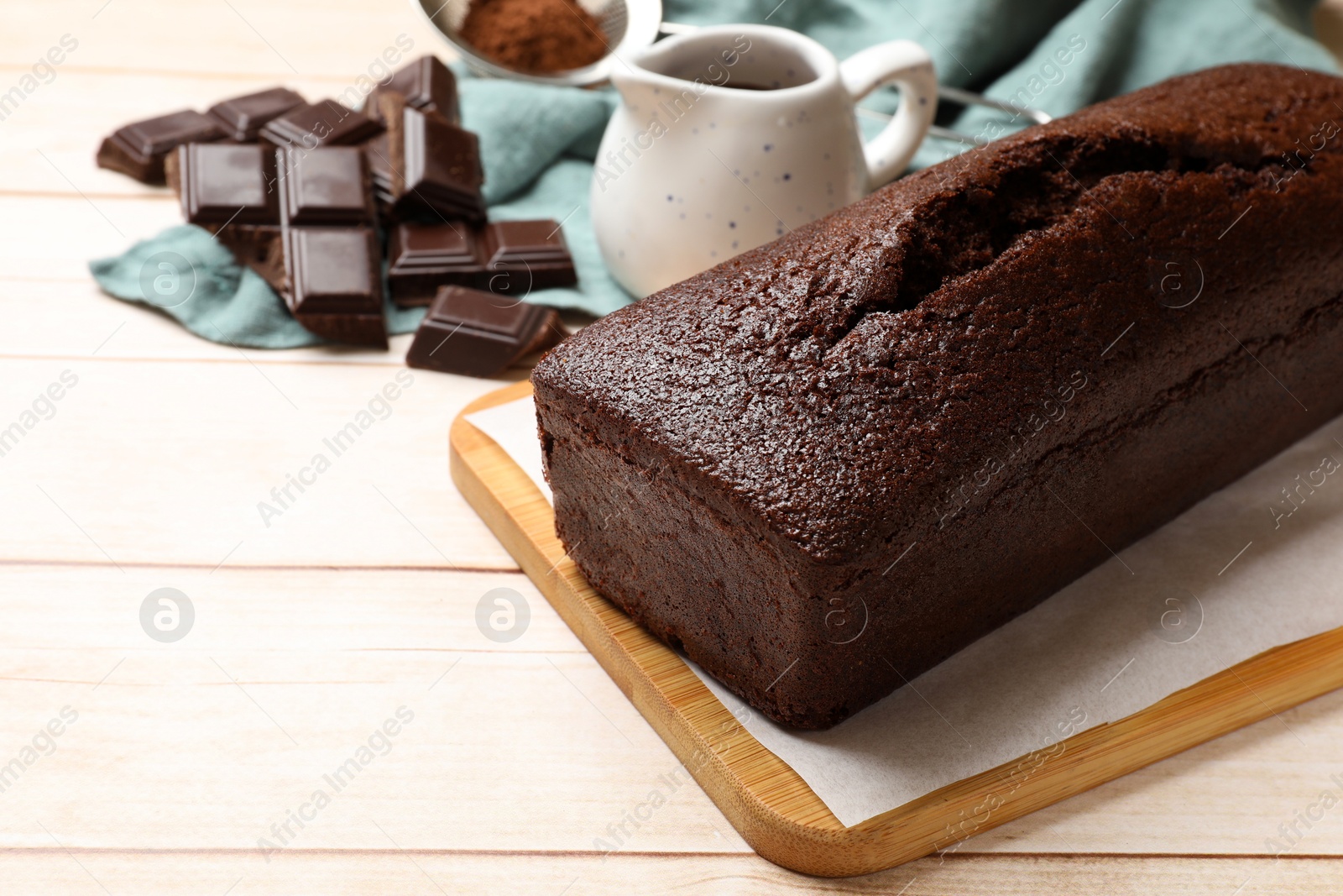 Photo of Tasty chocolate sponge cake and ingredients on white wooden table, closeup