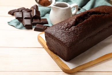 Photo of Tasty chocolate sponge cake and ingredients on white wooden table, closeup