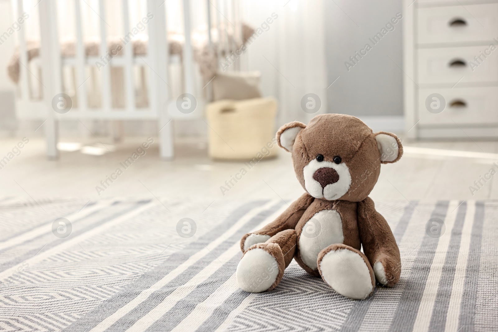 Photo of Cute teddy bear on floor in child room, space for text