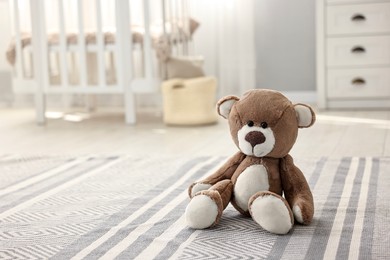 Photo of Cute teddy bear on floor in child room, space for text