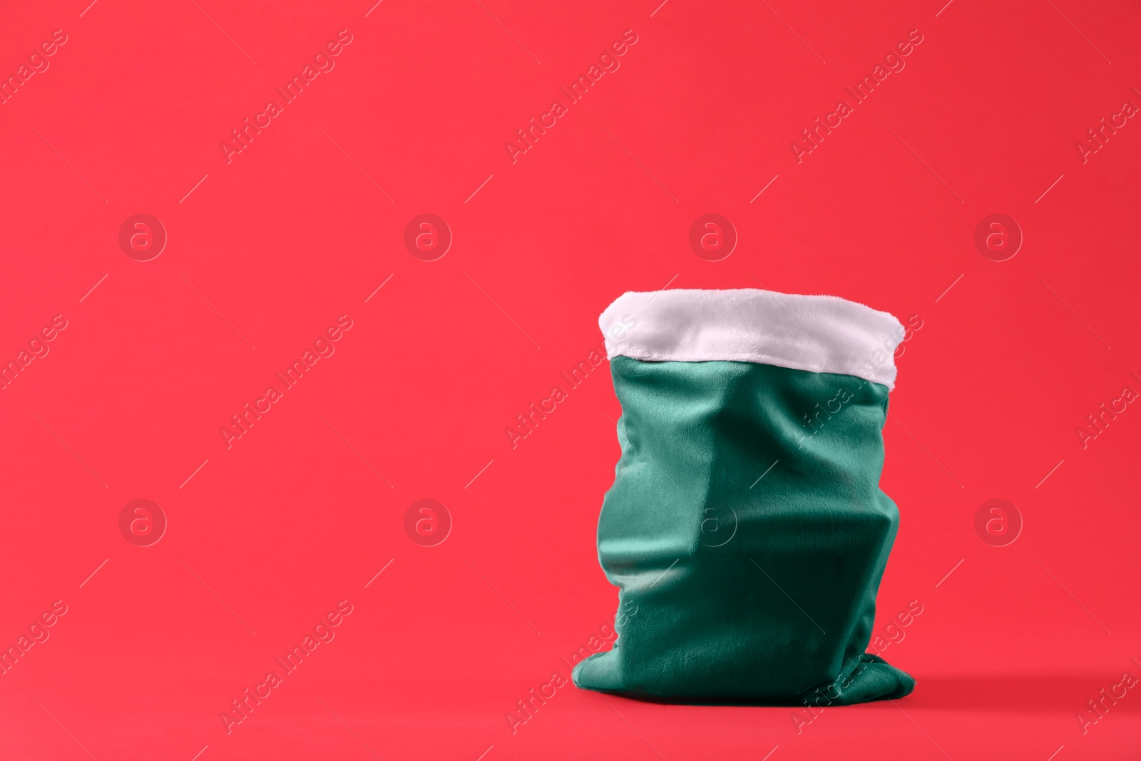 Photo of Green Santa Claus bag on red background, space for text