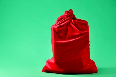 Red Santa Claus bag on green background, space for text