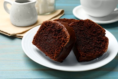 Photo of Slices of tasty chocolate sponge cake on light blue wooden table, closeup