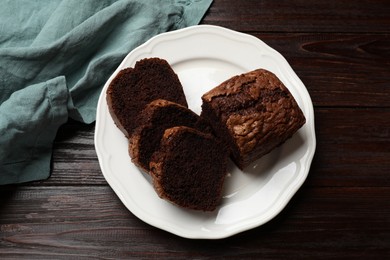 Photo of Delicious cut chocolate sponge cake on wooden table, top view