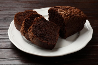 Photo of Delicious cut chocolate sponge cake on wooden table, closeup