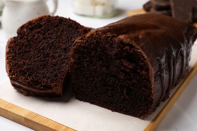 Photo of Delicious chocolate sponge cake on white tiled table, closeup