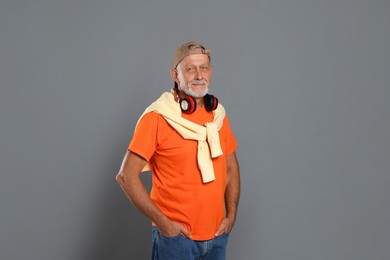 Portrait of handsome senior man with headphones on grey background