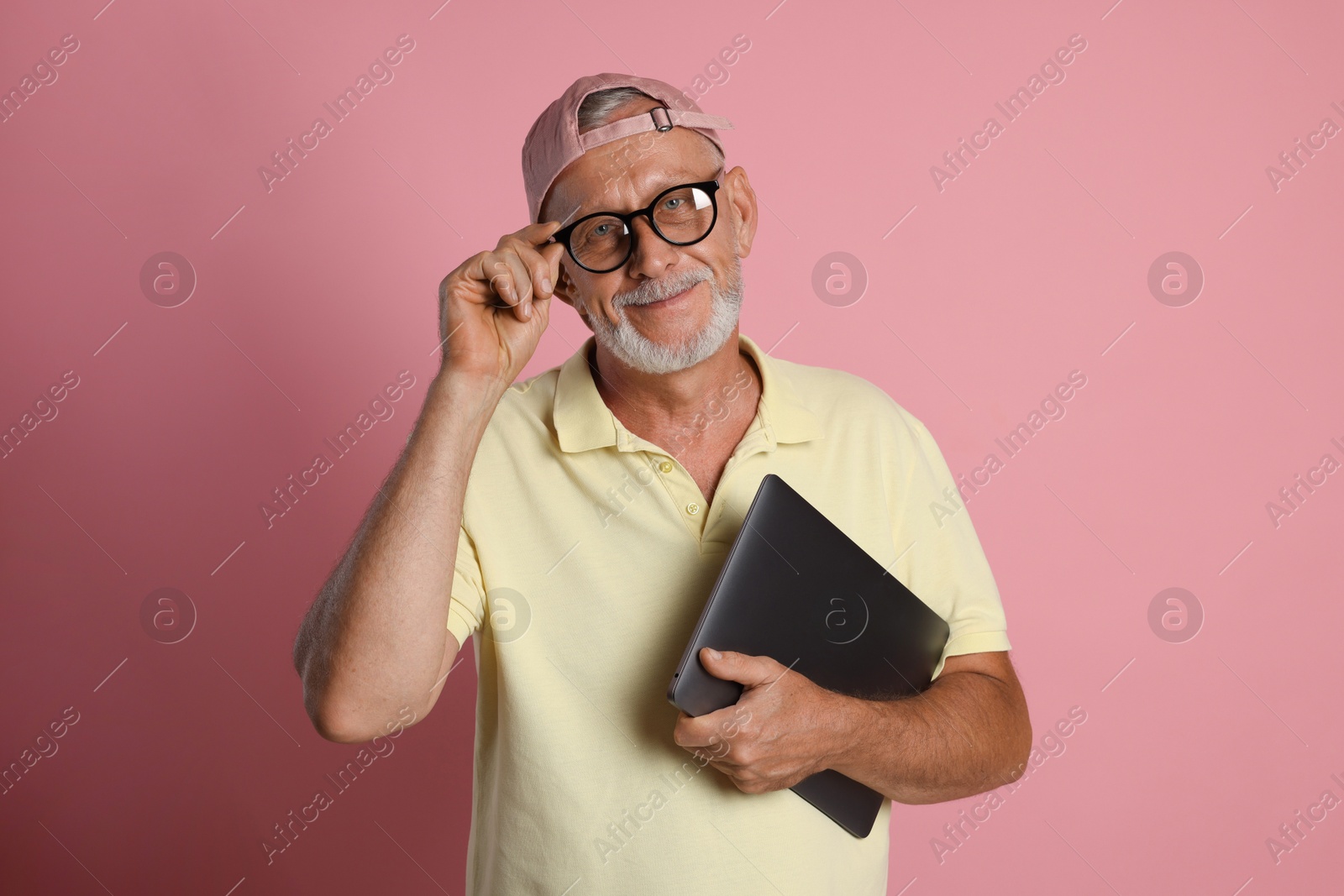 Photo of Portrait of handsome senior man with laptop on pink background