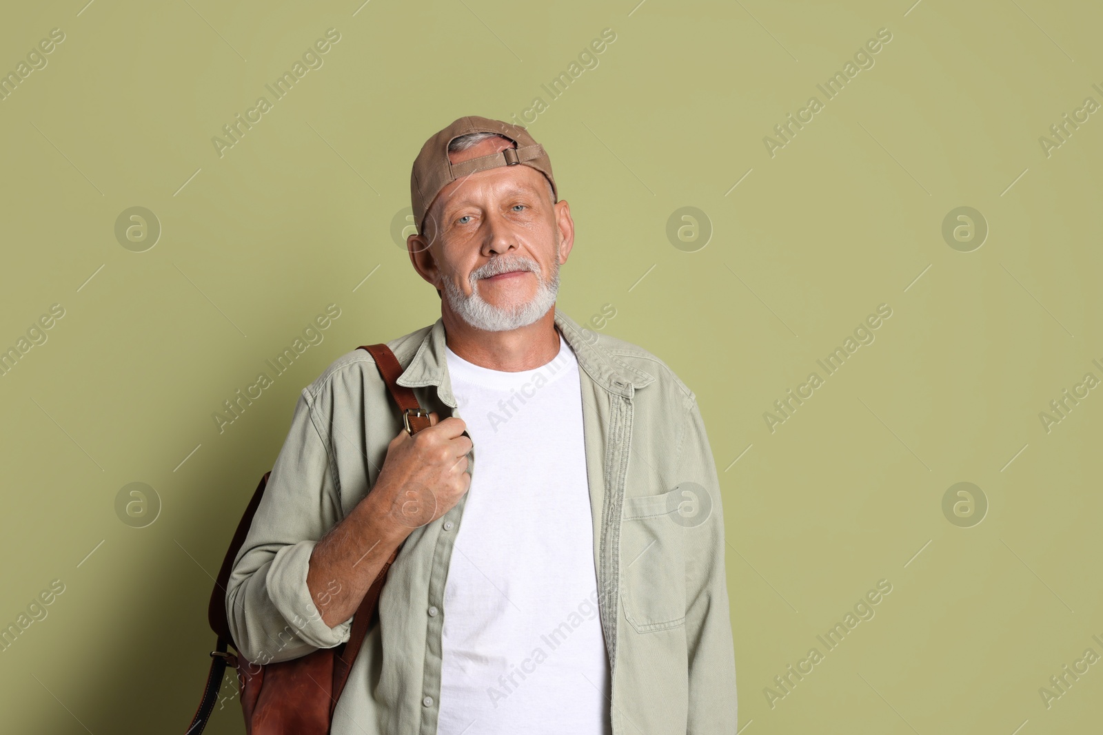 Photo of Portrait of handsome senior man with backpack on green background. Space for text