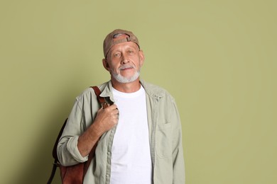 Photo of Portrait of handsome senior man with backpack on green background. Space for text