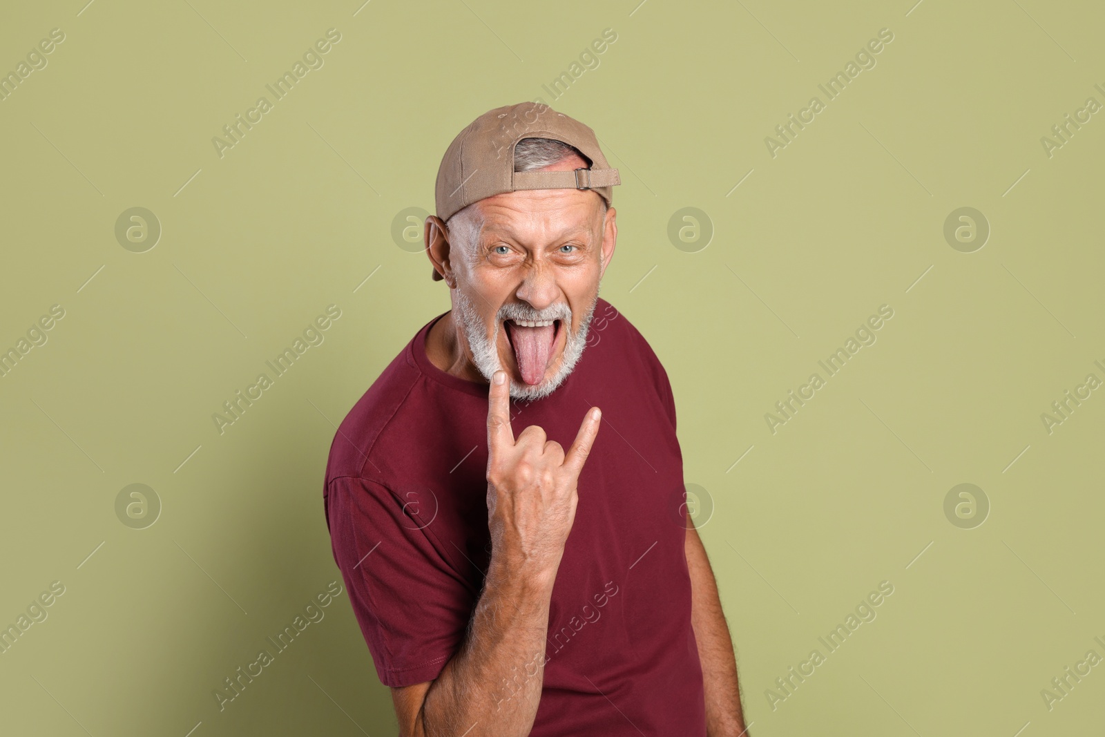 Photo of Portrait of emotional senior man showing rock gesture on green background