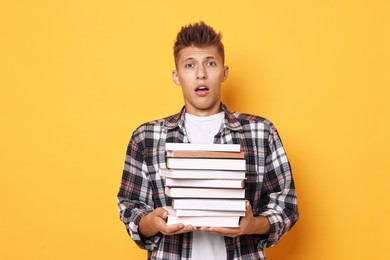 Young student with stack of books having stress before exam on yellow background