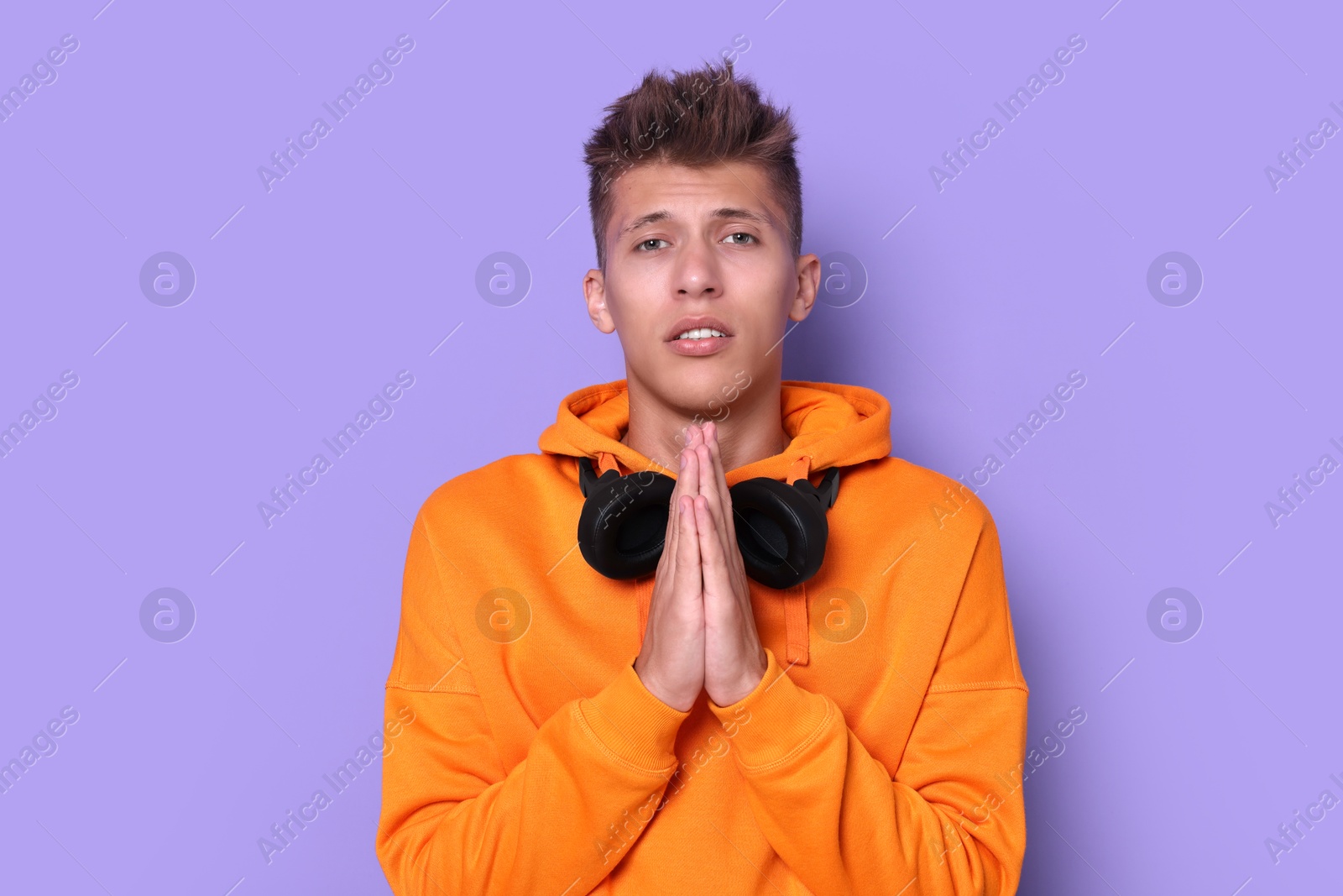 Photo of Young student praying for good exam result on violet background