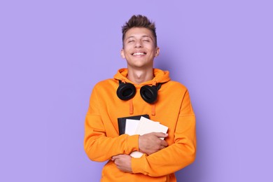 Photo of Young student with books happy about his good exam result on violet background