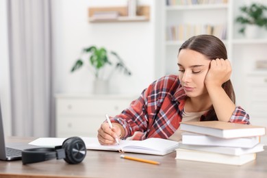 Photo of Student taking notes while studying at table indoors