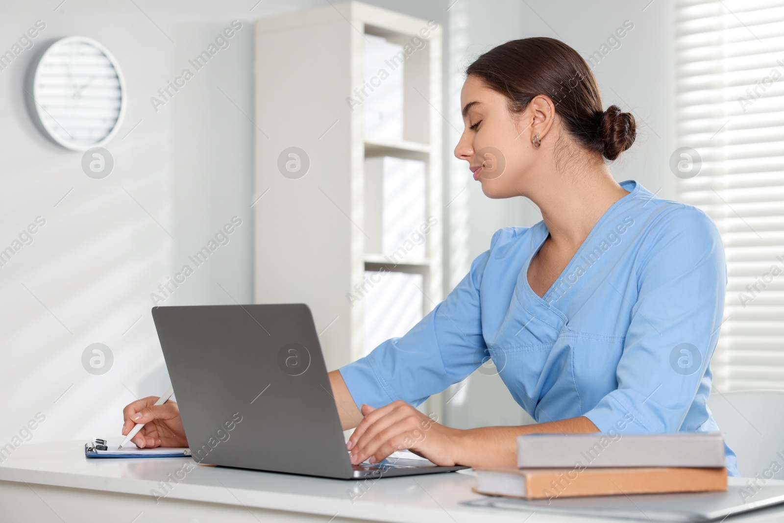 Photo of Medical student studying with laptop at table indoors