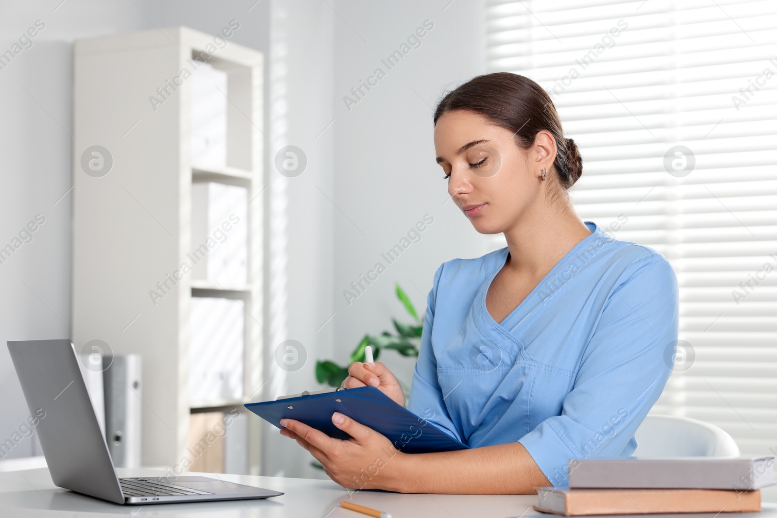 Photo of Medical student taking notes while studying at table indoors