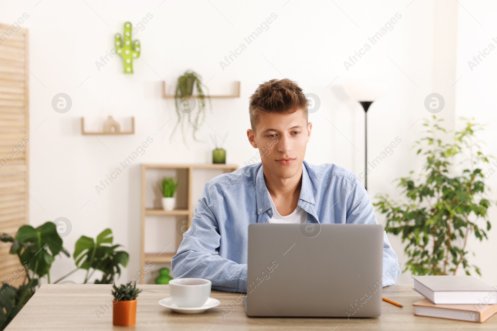 Photo of Student studying with laptop at wooden table indoors